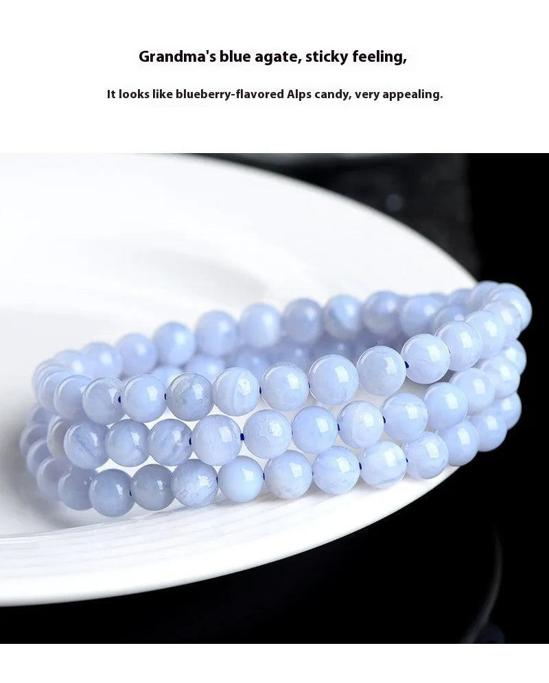 A blue agate bracelet with a natural striped pattern and scattered beads on a wrist.
