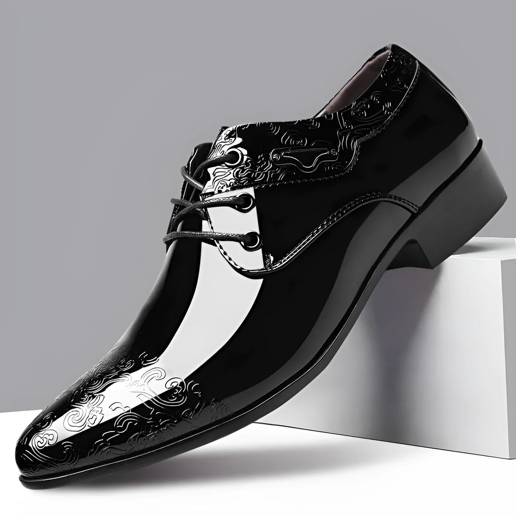 Glossy black men's business formal shoes with patent finish, pointed toe, and carved detail on a neutral background
