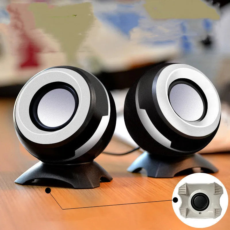 Pair of compact USB-powered desktop speakers in black and gold finish beside laptop computer