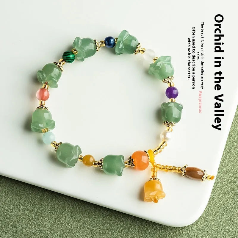 Close-up of a carved orchid bead jade bracelet in aventurine orchid colour on a wrist.