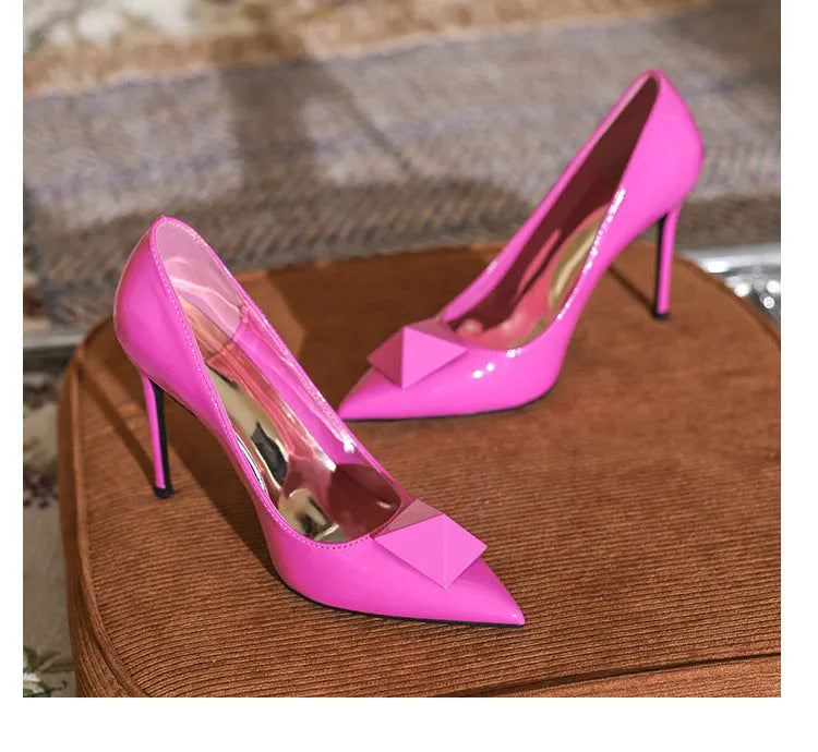 Pink women's patent leather pointed toe stiletto high heels with a buckle strap on a low-top.