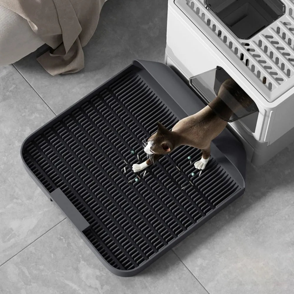 Large black cat litter pedal with slanted mouth and textured grooves beside a litter tray