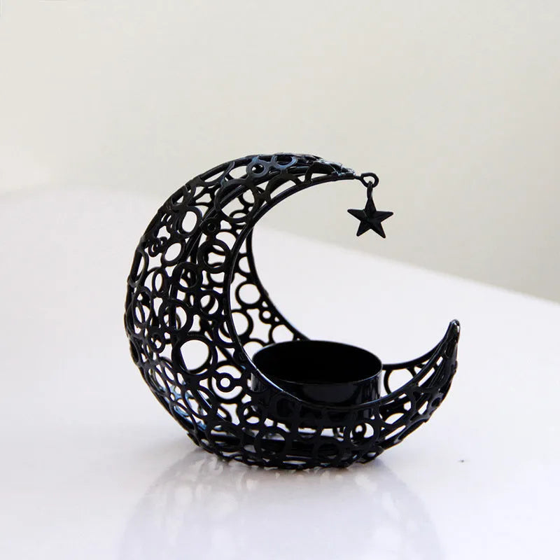 Gold metal crescent moon candle holder with hollow design on a dark surface