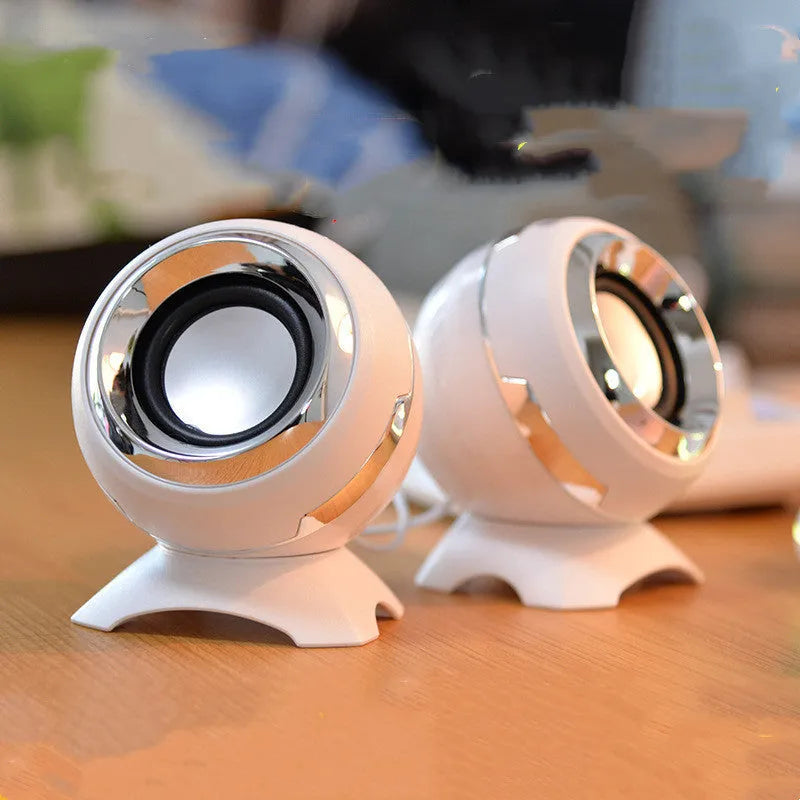 Pair of compact USB-powered desktop speakers in black and gold finish beside laptop computer