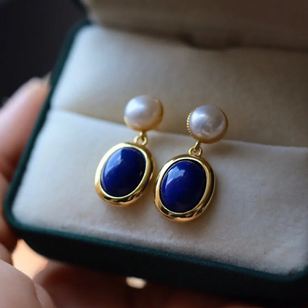 A pair of simple sterling silver stud earrings with a blue lapis lazuli pearl drop.