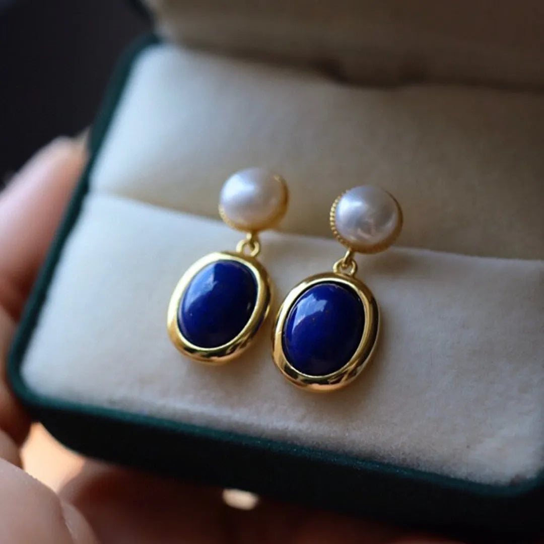 A pair of simple sterling silver stud earrings with a blue lapis lazuli pearl drop.