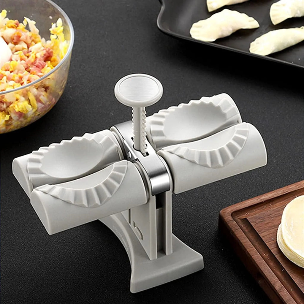 White double-head manual dumpling maker mould made from stainless steel and plastic with an anti-slip base.