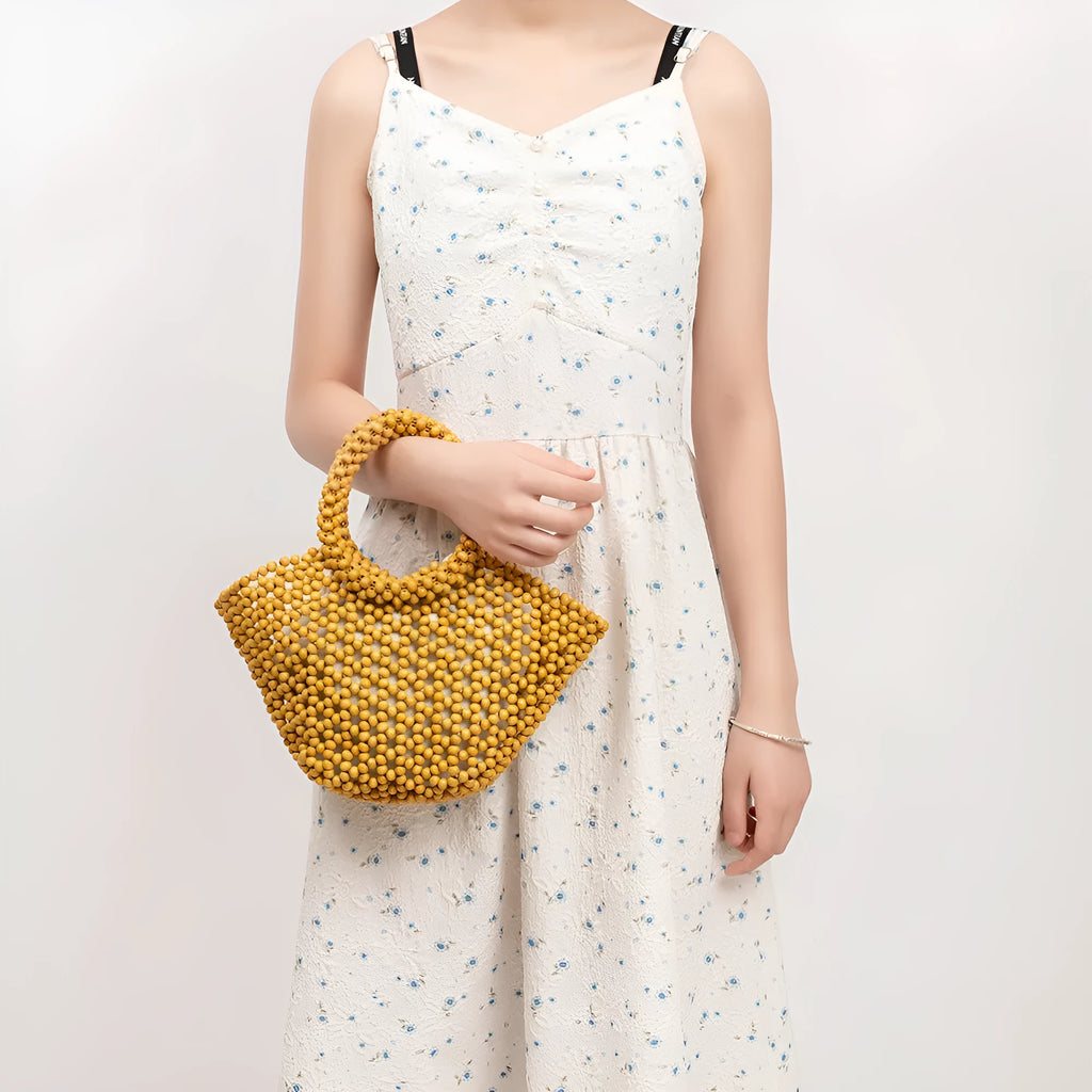 Hand-woven dumpling-shaped beach bag with wooden beads in milky white.