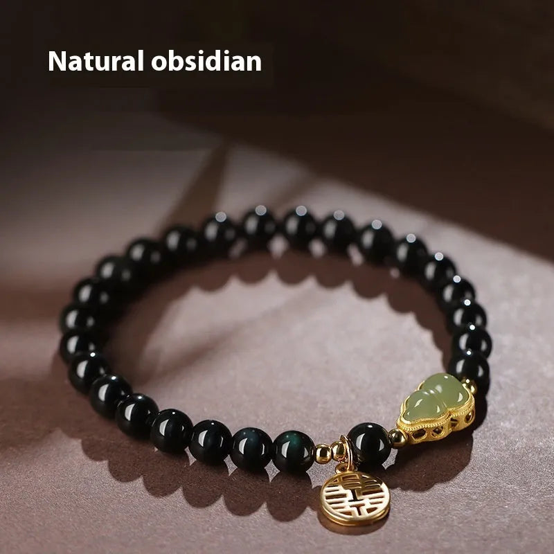 Black obsidian bracelet with carved Hetian jade gourd charm showing geometric patterns