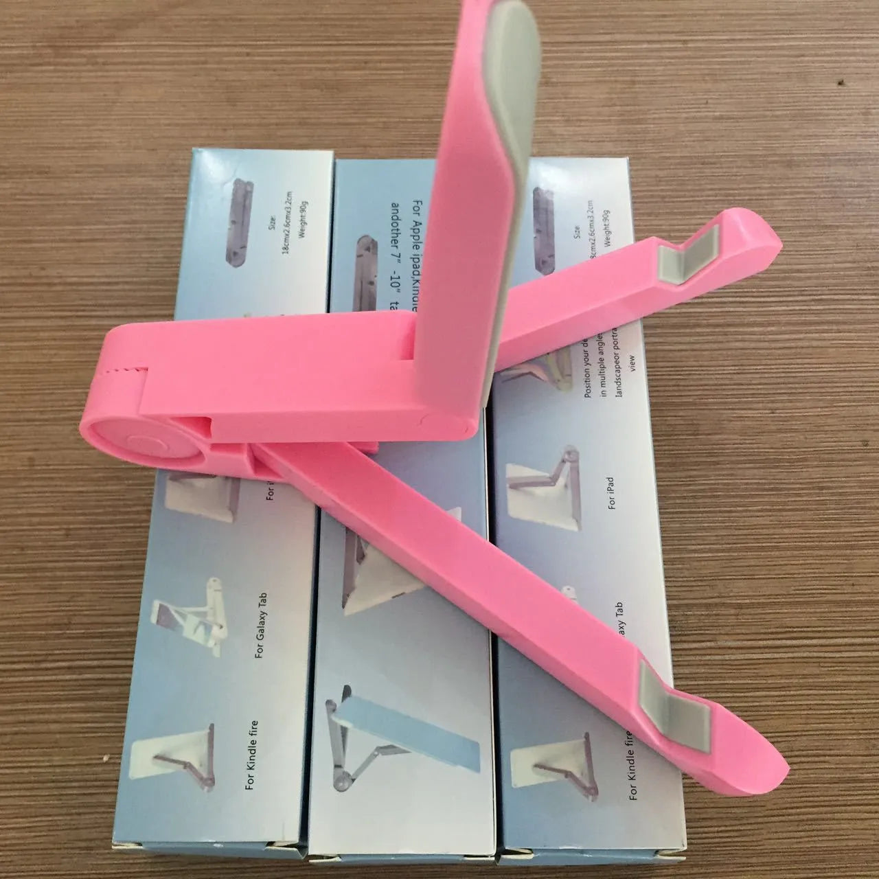 Black foldable tablet holder standing upright holding a tablet, shown next to its folded flat profile.