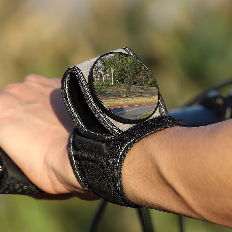 Black nylon cycling wrist rear-view mirror showing strap attachment and mirror positioning