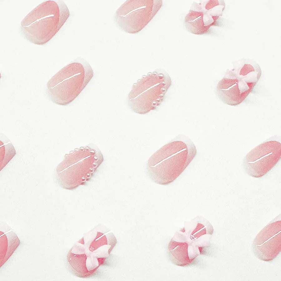 Short white French tip false nails with cute bow and starry sky designs, shown with glue bottles.