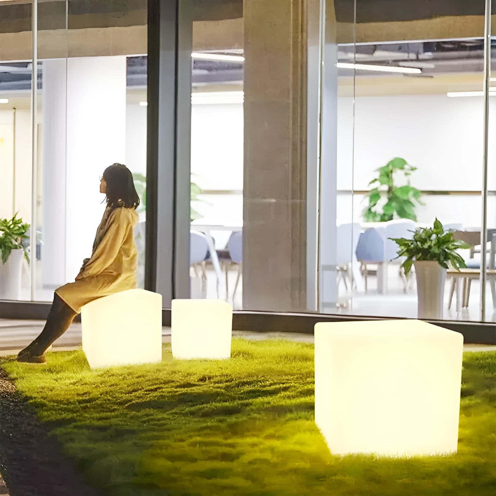 A modern, square white LED cube light functioning as a waterproof outdoor stool.