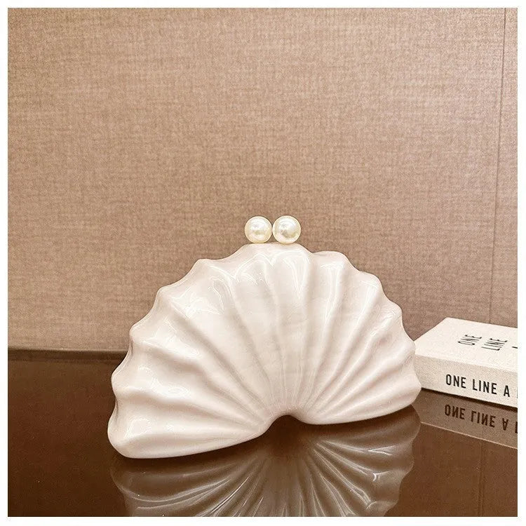 Acrylic shell-shaped clutch bag in champagne colour with chain detail on solid background