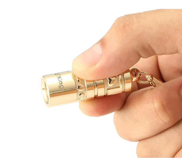 Gold-coloured zinc alloy mini portable LED flashlight on a keyring.