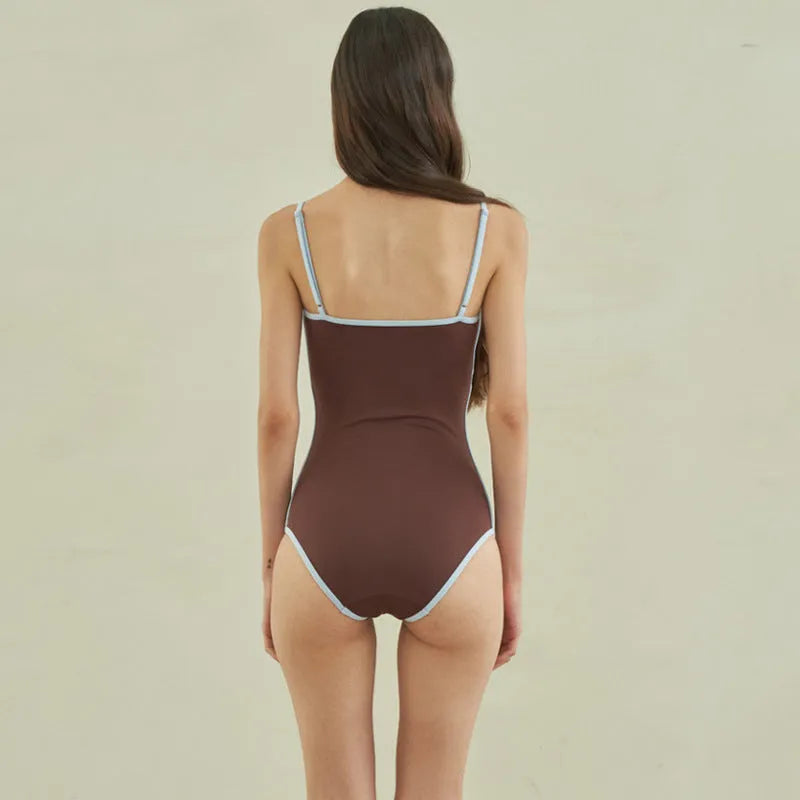 Brown women's one-piece swimsuit with a triangle pattern top on a hanger.