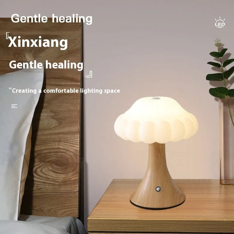 Small mushroom-shaped rechargeable night light in wood grain colour with touch control on desk.