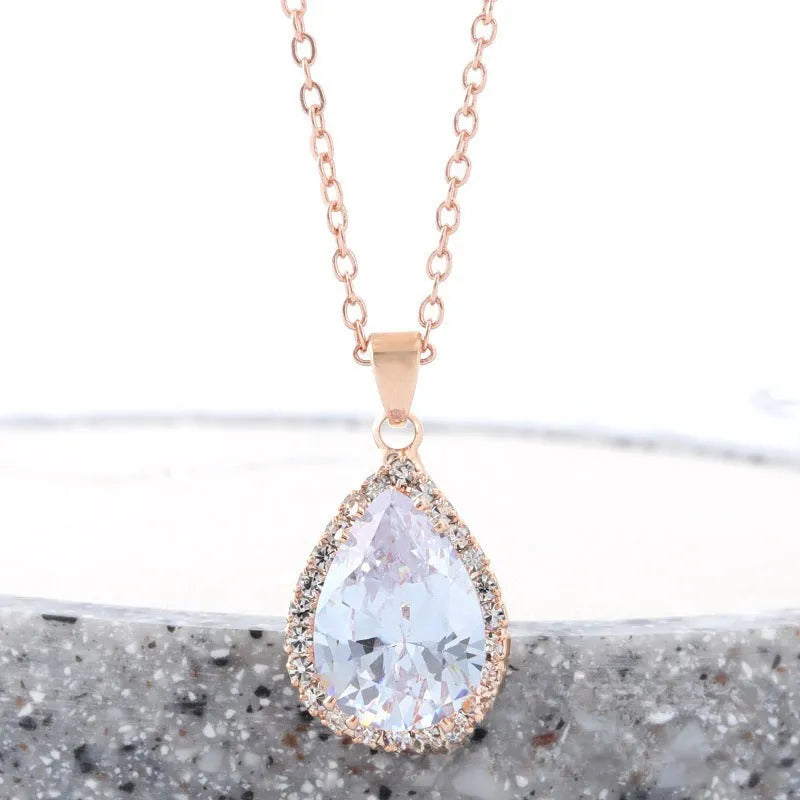 Close-up of a rose gold tone drop shape necklace with rhinestone details on a geometric pendant.