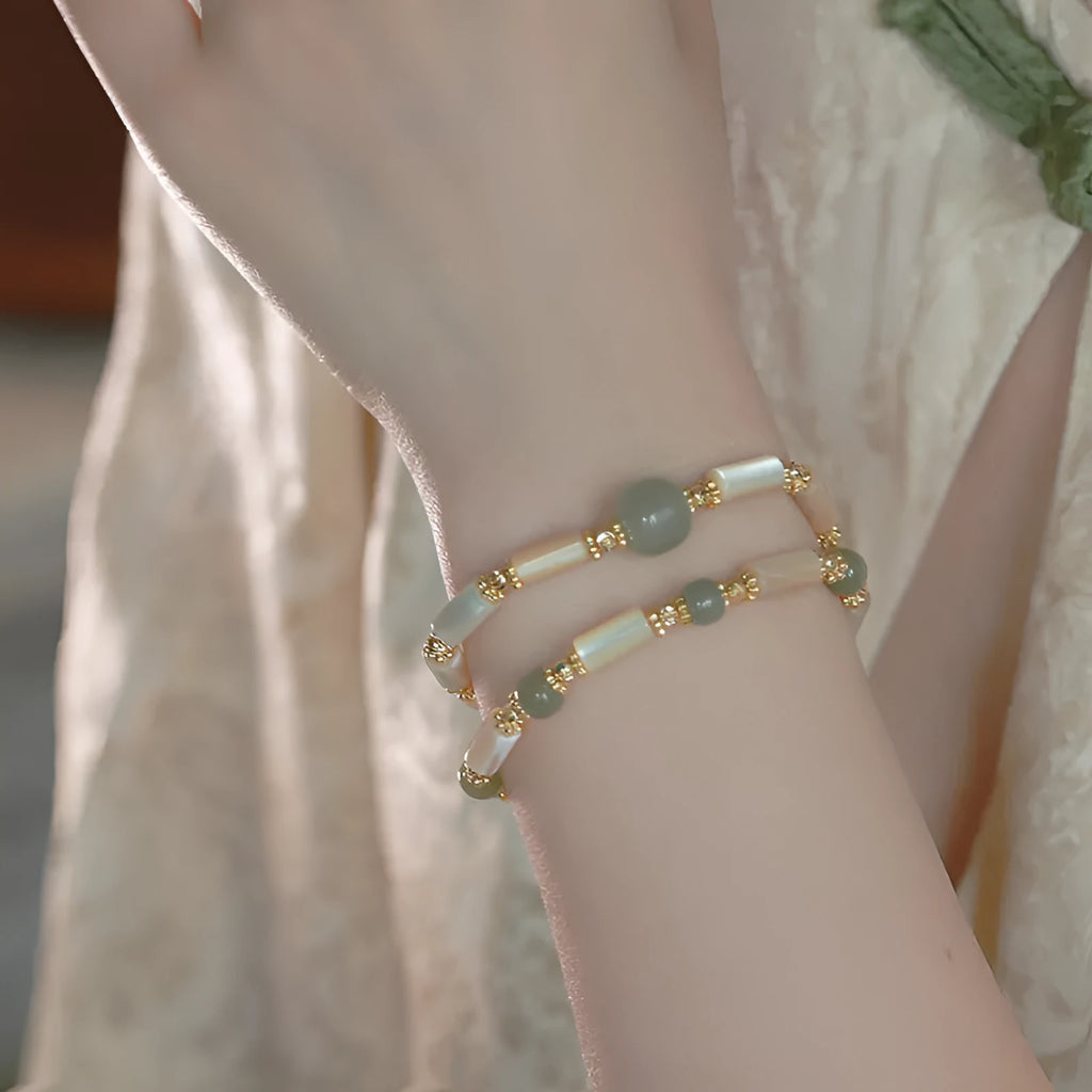 Simple women's bracelet made of round white Hetian jade beads on a wrist.