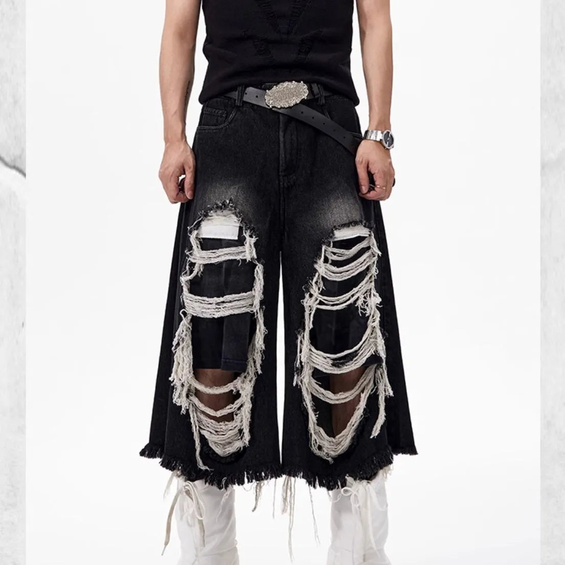 Woman wearing black distressed wide leg cropped jeans with ripped patches.