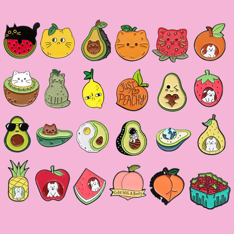 Colourful cartoon fruit and letter design on a silver-toned metal brooch pin.
