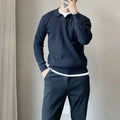 Man wearing a loose striped knitted sweater with a lapel collar in light grey.
