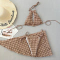 Brown seersucker lace-up three-piece bikini swimsuit for women laid flat, showing top, pants, and skirt.