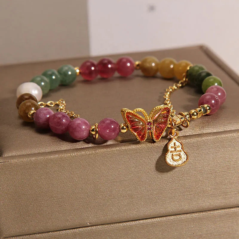 Close-up of a women's agate bracelet with a green tourmaline butterfly-shaped gourd charm on a white background.