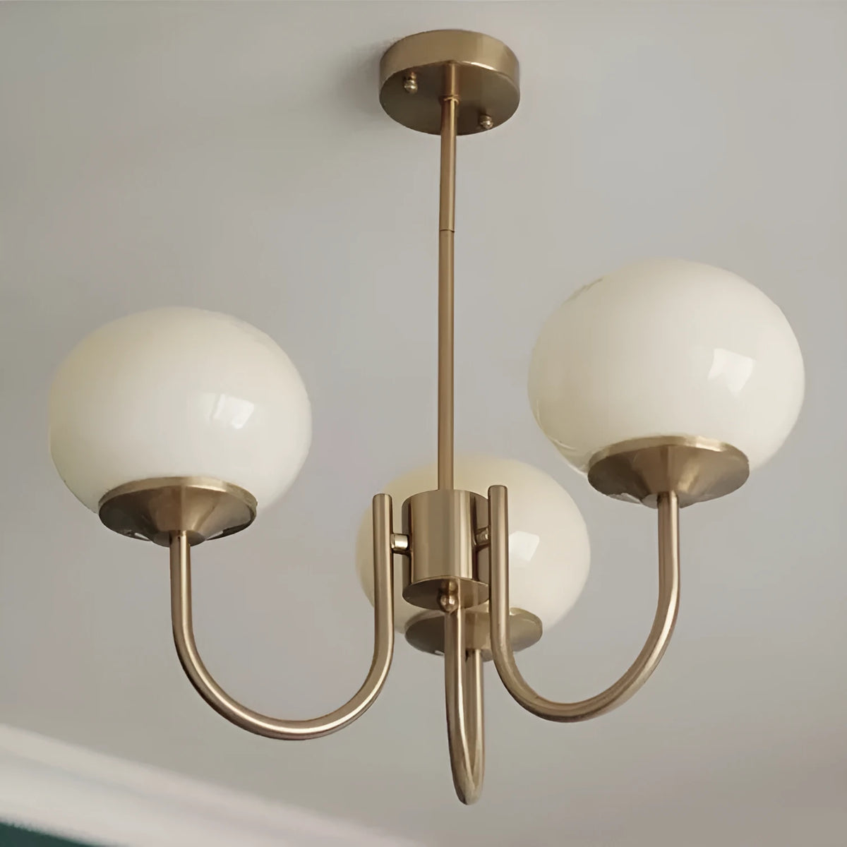 Three-head chandelier with iron frame and glass ball lampshades in copper finish