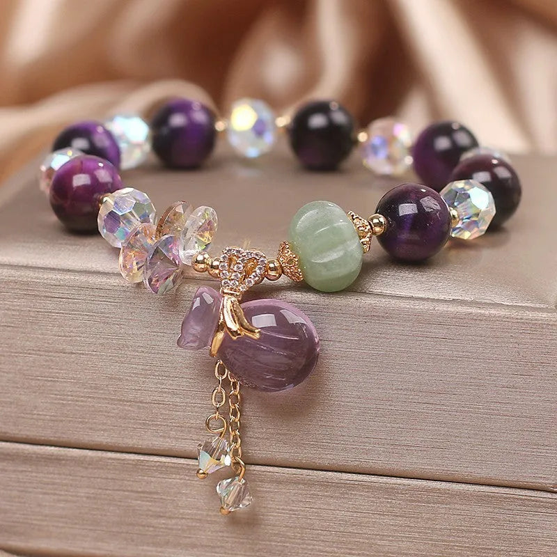 Women's purple Tigereye pendant crystal bracelet with rhinestones on a forest-style background.