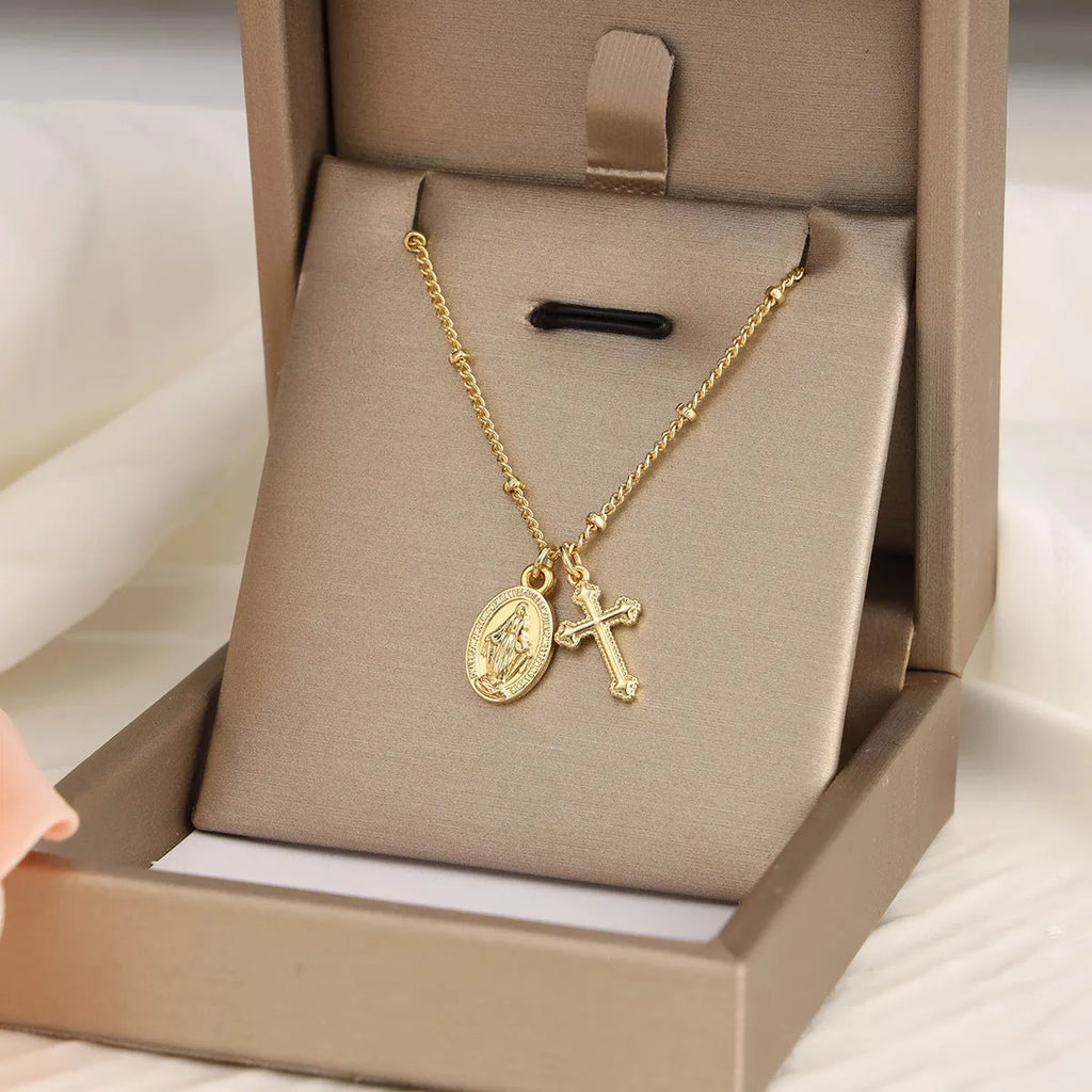 Gold geometric cross necklace with a Virgin Mary ornament pendant on a chain.