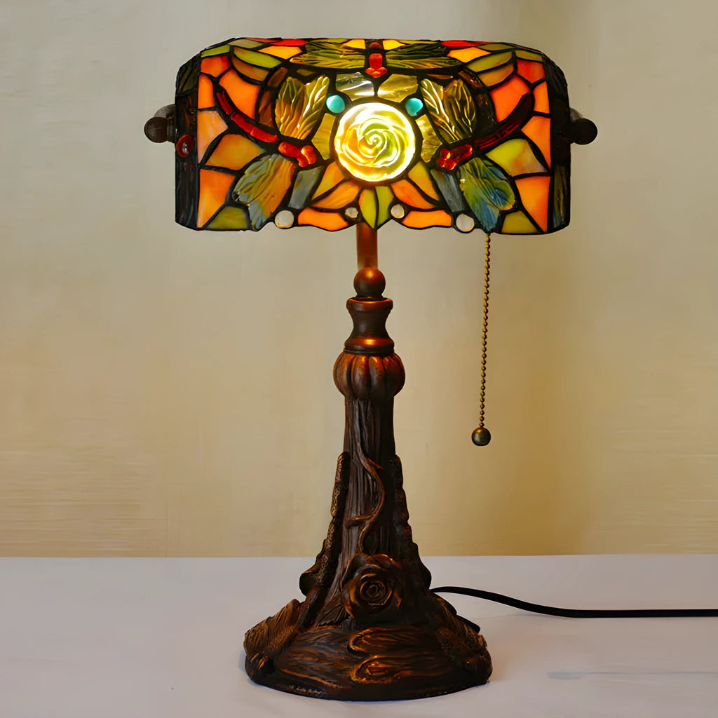 Tiffany stained glass table lamp on a desk, showing its coloured shade and resin base.