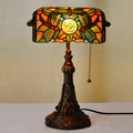 Tiffany stained glass table lamp on a desk, showing its coloured shade and resin base.