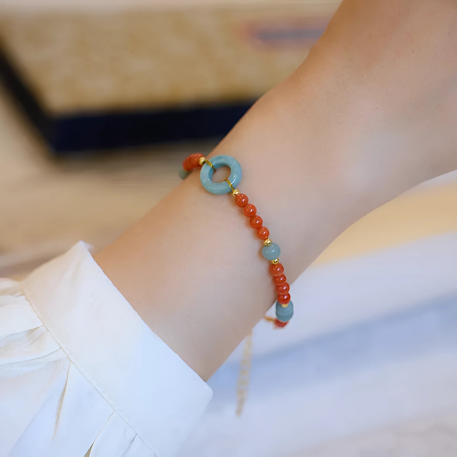 Close-up of a women's south red agate bracelet with geometric beads and a safety buckle clasp on a wrist.