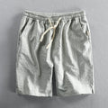 Man wearing striped light grey casual cotton shorts with a straight leg and elastic waistband.