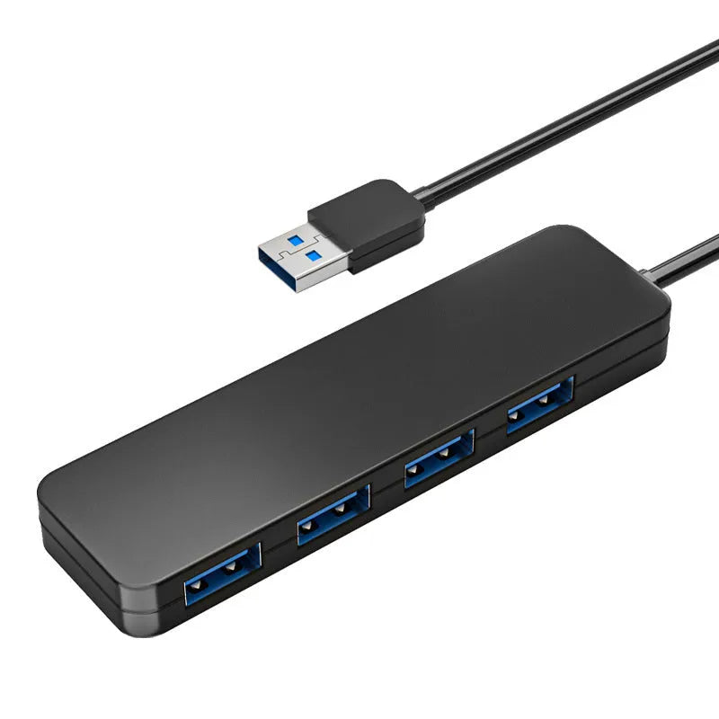 Black USB 3.0 hub with four ports and a 30 cm attached cable on a desk.