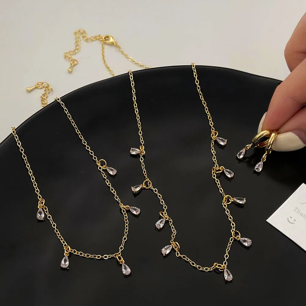 A women's zircon jewellery set showing a geometric meteor shower necklace, matching earrings, and an anklet on a white background.