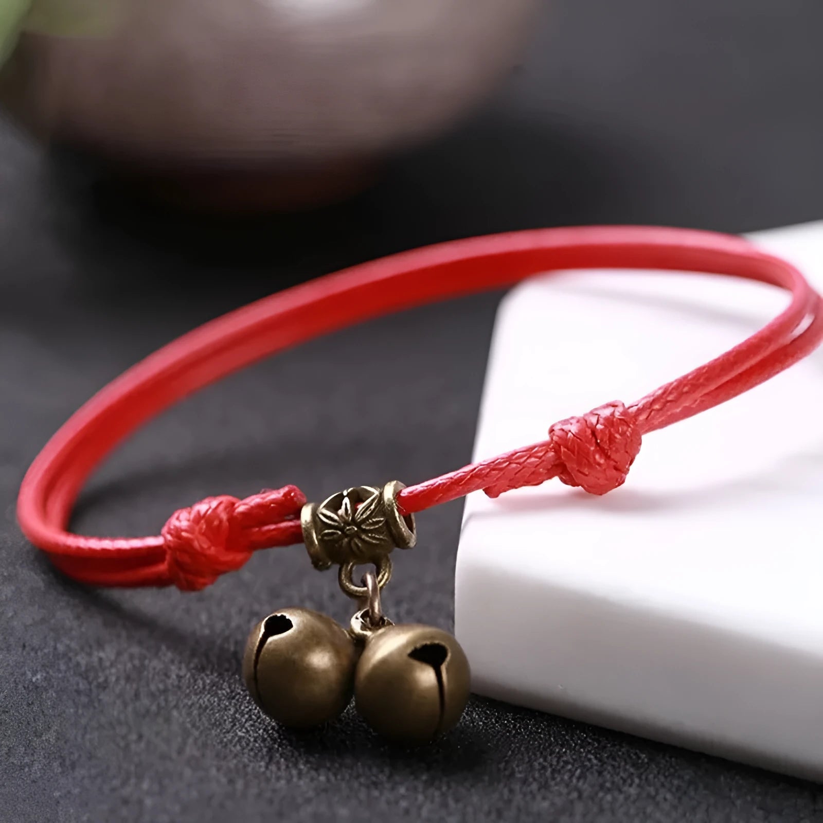Black nylon rope dog collar with a shiny brass bell on a wooden surface.