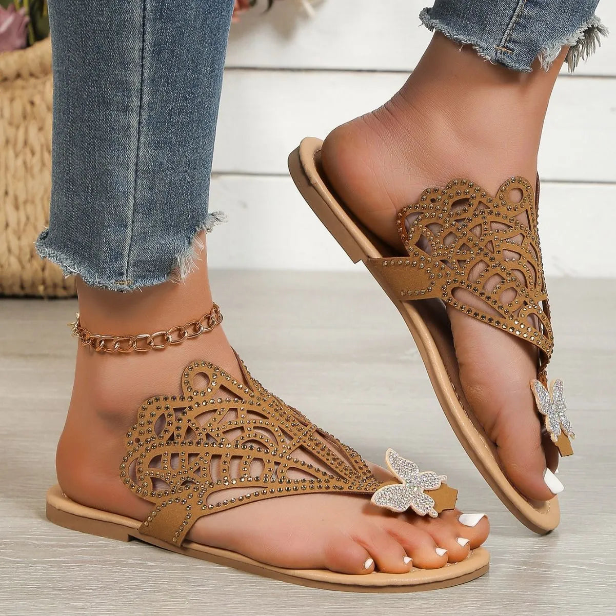 Women's black slip-on sandals with rhinestone decoration and hollow-out design on a flat rubber sole.