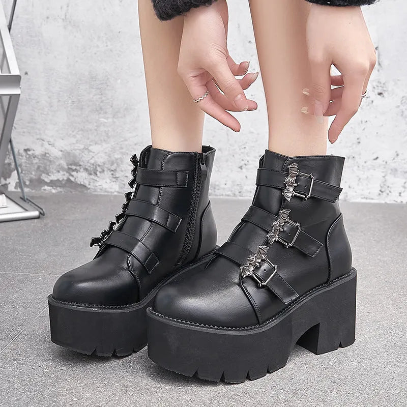 Black women's punk ankle boots with bat buckle and side zip on a thick sole.
