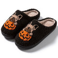 Black and white Halloween slippers with pumpkin pattern, plush lining, and textured non-slip rubber soles.