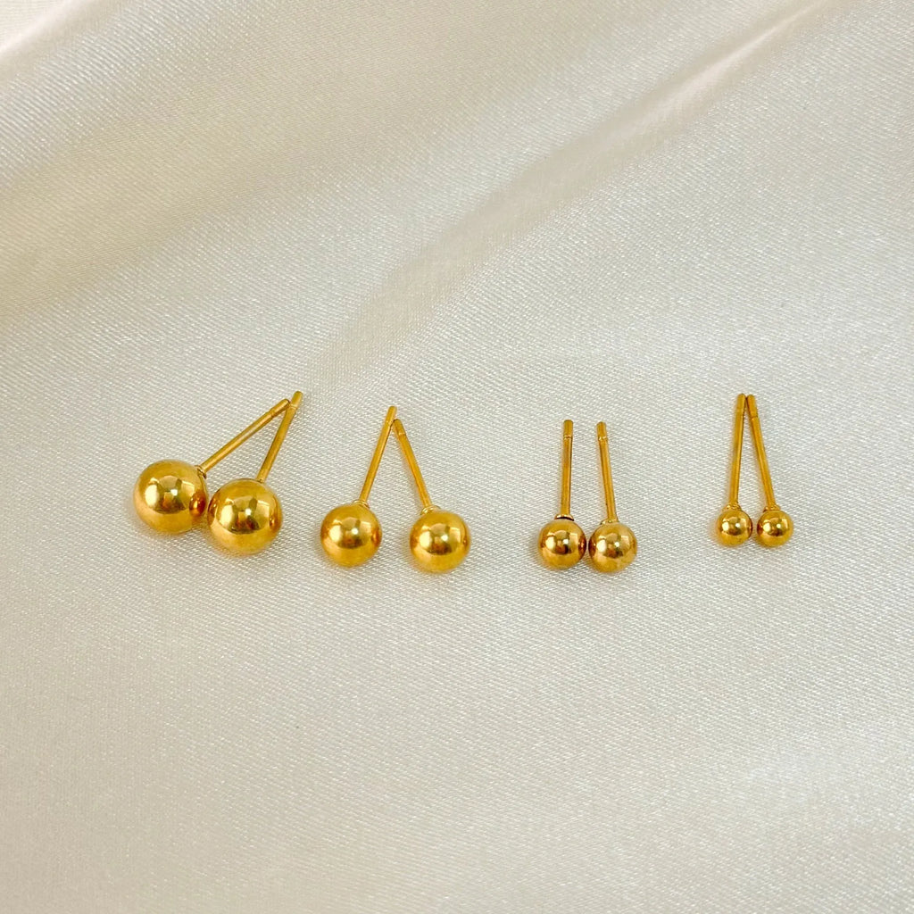 Minimalist round ball stud earrings in gold and silver finishes, showing different size options on a plain background.