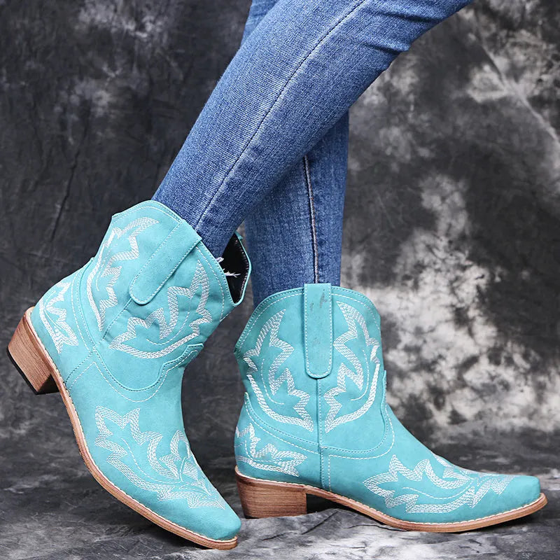 Blue women's cowboy boots with embroidery and a low wedge heel on a wooden floor.