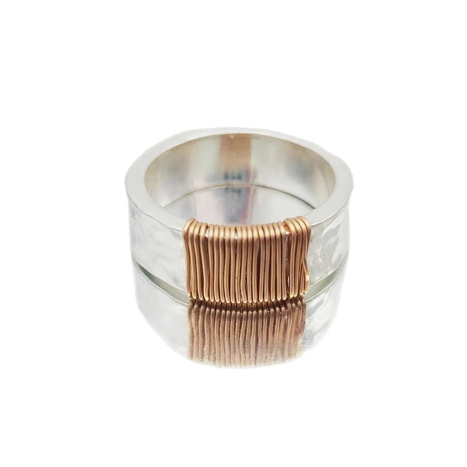 Geometric copper ring bracelet with a wide face and irregular coil design in a silver gold colour.