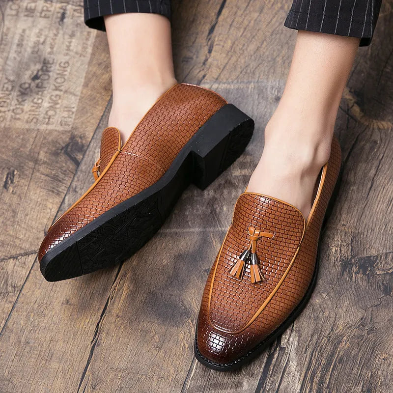 Men's black pointed slip-on business shoes with a tassel detail on the artificial PU leather upper.