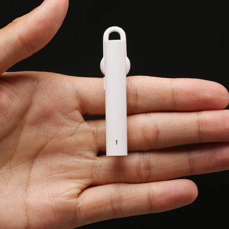 Compact black and white wireless Bluetooth headset for hands-free calls, shown next to a size scale.