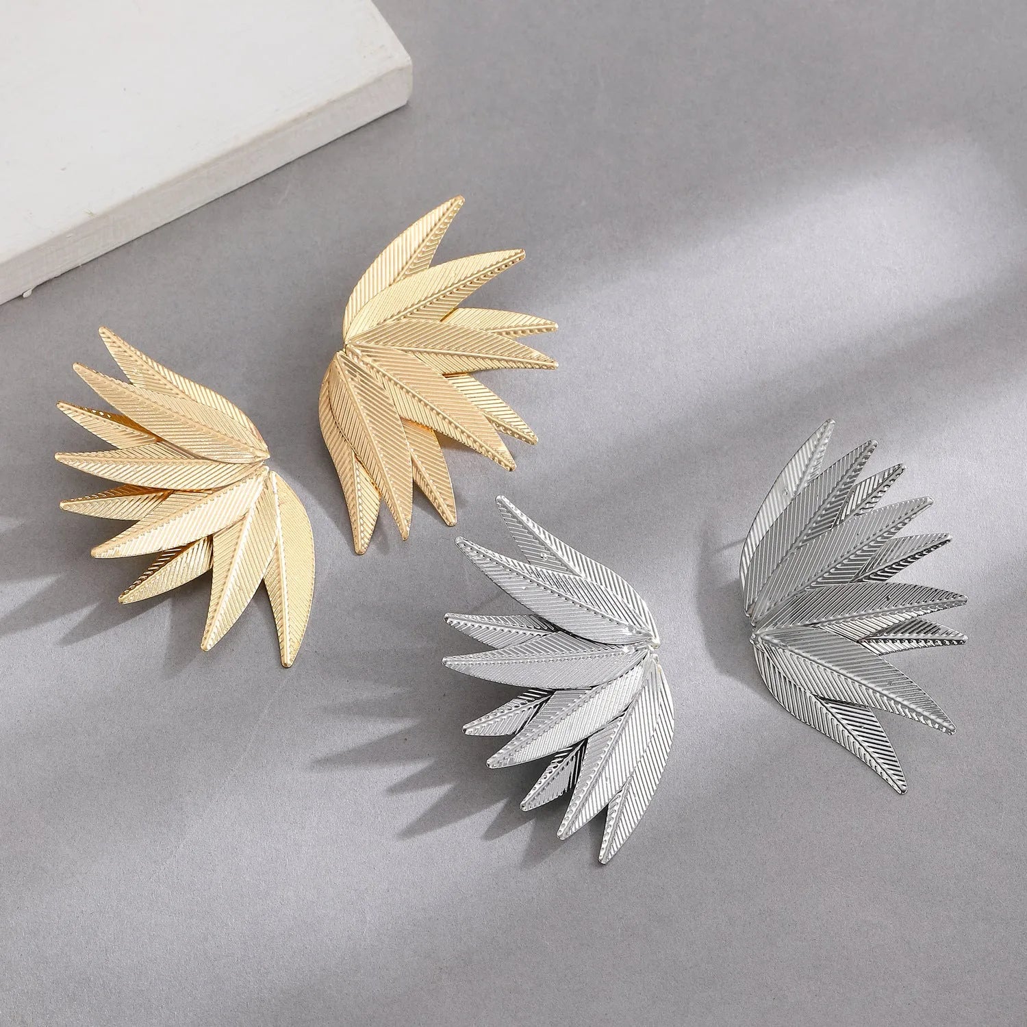 Gold and white leaf-shaped alloy patch earrings with botanical design details