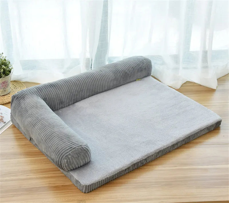 A corduroy pet sofa dog bed with bolsters, shown in a grey colour, placed on a hardwood floor.