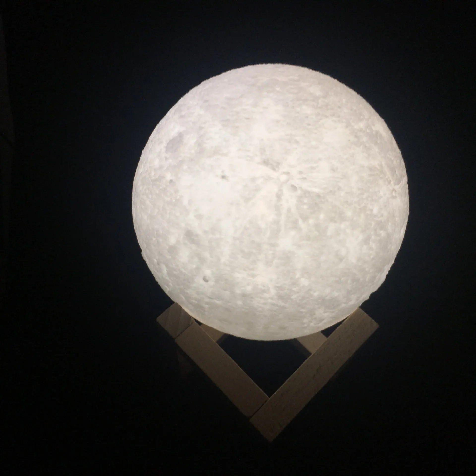 3D printed spherical moon lamp showing lunar surface texture on wooden holder