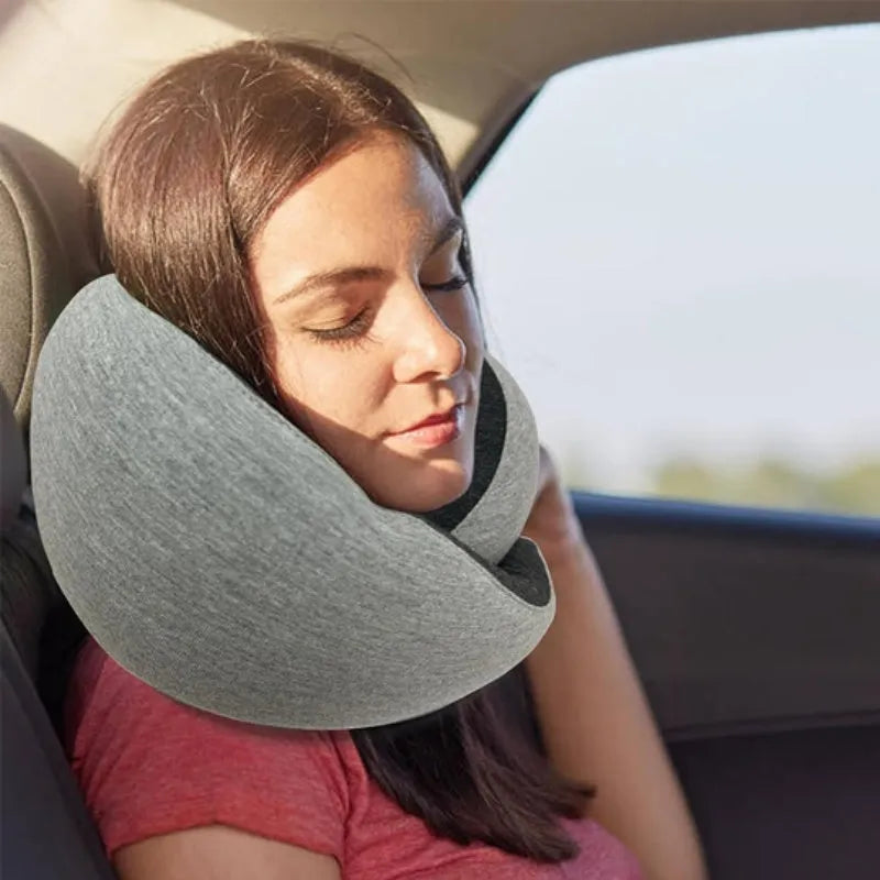 U-shaped navy blue memory foam travel neck pillow rolled up next to a mobile phone showing compact size